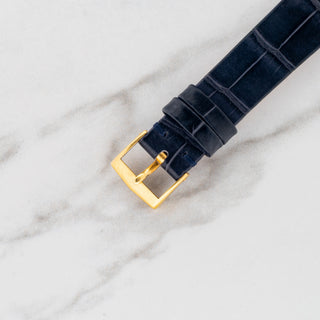 Top view of the original signed 18k yellow gold AW pin buckle attached to a navy blue alligator strap