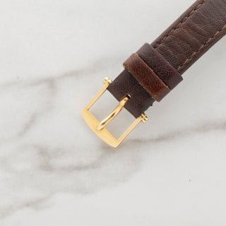 Close-up view of the authentic 18k yellow gold Breguet pin buckle on a brown leather strap
