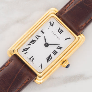 Angled shot highlighting the stepped 18k yellow gold case profile and white stretched Roman numeral dial of a Cartier Tank