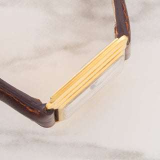 Side view displaying the distinctive stepped case lines and slim profile of an 18k gold Cartier Tank