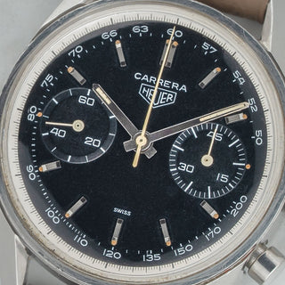 Macro close-up of the pristine black dial, inner tachymeter ring, and warm tritium lume plots on a vintage Heuer Carrera 3647NT