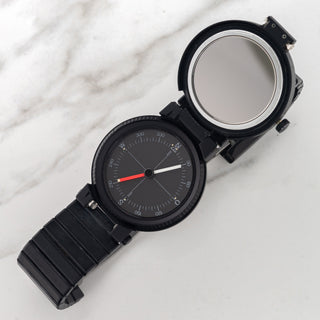 Hinged case opened on an IWC Porsche Design 3551 revealing the hidden liquid-damped compass and emergency mirror
