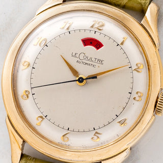 Macro close-up shot of the brushed silver dial, applied gold Breguet numerals, dauphine hands, and red power reserve aperture on a LeCoultre Powermatic