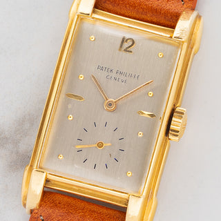 Macro close-up shot of the brushed silver dial, applied gold hour markers, 12 numeral, and sub-seconds register on a Patek Philippe 2417J