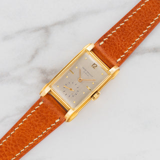 1950s Patek Philippe reference 2417J in 18k yellow gold with curved rectangular case and silver dial on a tan calfskin strap at Collectors Corner NY