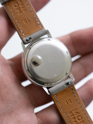 In-hand view of the backwinding mechanism on the solid white gold caseback of a Patek Philippe 3569