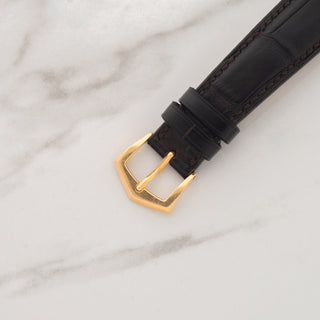 Close-up view of the authentic 18k rose gold signed Patek Philippe pin buckle on a dark alligator strap