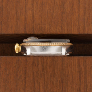 Horizontal profile detail showing the 18k yellow gold winding crown and fluted bezel edge of a Rolex 1601