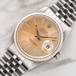 Angled shot highlighting the 18k white gold fluted bezel and tropical peach sunburst dial on a Rolex Datejust 16234