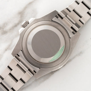 The clean stainless steel Oyster caseback with green factory sticker trace and brushed lug undersides on a Rolex 116710LN