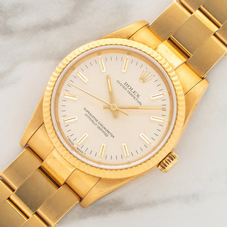 Angled shot highlighting the razor-sharp fluted bezel, unpolished 18k gold case, and silver dial on a Rolex 14238