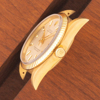 Angled top perspective showcasing the unpolished 18k gold case lines, deep hallmarks, and signed crown on a Rolex 14238
