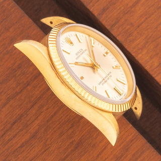 Angled top view highlighting the razor-sharp 18k gold lug proportions and silver dial on an unpolished Rolex 14238