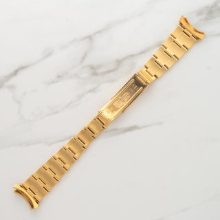 Underside view displaying the rivet link construction and hallmarks on an 18k yellow gold Rolex 7205 bracelet