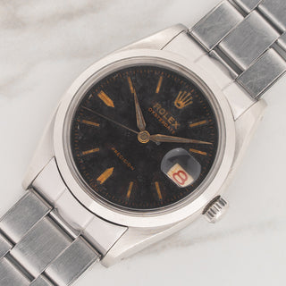 Angled view highlighting the smooth bezel, black gilt dial, and stainless steel case of a Rolex 6494