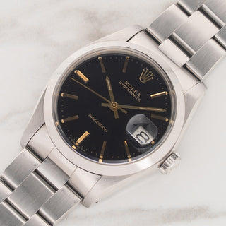 Angled view highlighting the smooth bezel, black glossy dial, and steel case lines of a Rolex Oysterdate 6694