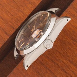 Angled top perspective showcasing the acrylic crystal, winding crown, and lug chamfers on a Rolex 6694