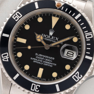 Macro close-up shot of the matte black dial, deep yellow tritium patina, matching hands, and dark pumpkin bezel pip on a Rolex 16800