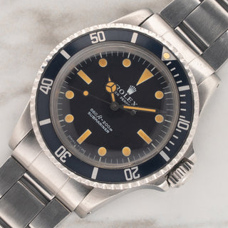 angled shot highlighting the faded navy aluminum bezel insert and deep pumpkin patina dial of a 1975 Rolex Submariner 5513