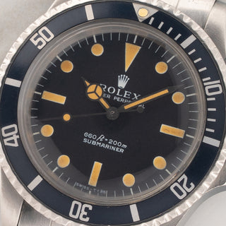 Macro close-up shot of the matte black two-line dial, vibrant pumpkin patina tritium plots, color-matched hands, and pearl on a Rolex Submariner 5513