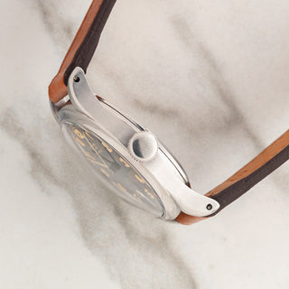 Side profile view showcasing the stainless steel case architecture, winding crown, and domed acrylic crystal on a 1940s Tissot Antimagnetique