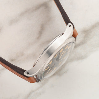 Side profile view displaying the thick lug proportions and polished stainless steel case on a 1940s Tissot Antimagnetique