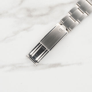 Close-up shot of the authentic Tudor shield logo stamped on the folding watch clasp of a rivet bracelet