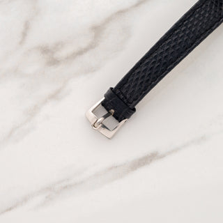 Close-up view of the authentic signed Universal Genève stainless steel pin buckle on a black textured watch strap