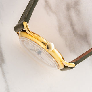 Side profile view showcasing the slim 18k yellow gold case, winding crown, and acrylic crystal on a Universal Genève 10750