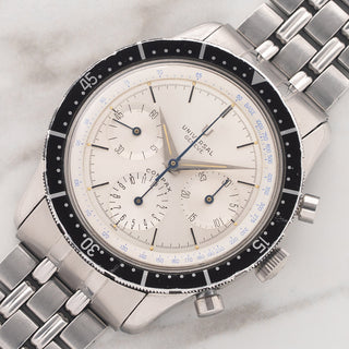 Angled view showcasing the 40mm case, silver sunburst dial, and black rotating bezel of a Universal Genève Compax 22703.