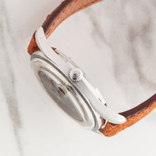 Side profile view showcasing the slim stainless steel case architecture, signed winding crown, and domed crystal on a Universal Genève Polerouter Date