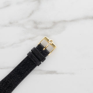 Close-up of the authentic 18k yellow gold signed Universal Genève pin buckle attached to a black leather strap