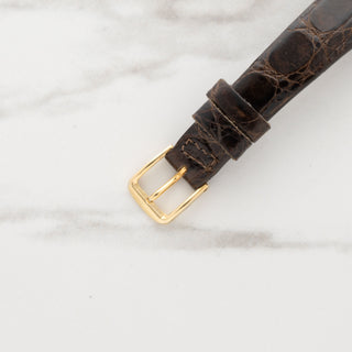 Close-up view of the gold-toned pin buckle on a brown leather crocodile-grain strap for a ladies Vacheron Constantin