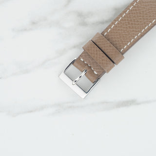 Close-up view of the stainless steel pin buckle on a taupe grained leather watch strap